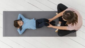 PT assisting a girl with a bridge exercise Click to go to our Evaluations and Consultations page