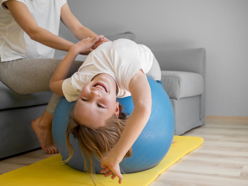 Child on a exercise ball Girl performs assisted exercise participating in pediatric physical therapy.