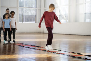 Children in a Fitness class taking turns on an agility ladder.
