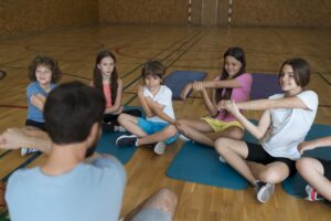 Therapist directing group of children in shoulder stretches Click to go to our Physical Therapy Treatment page